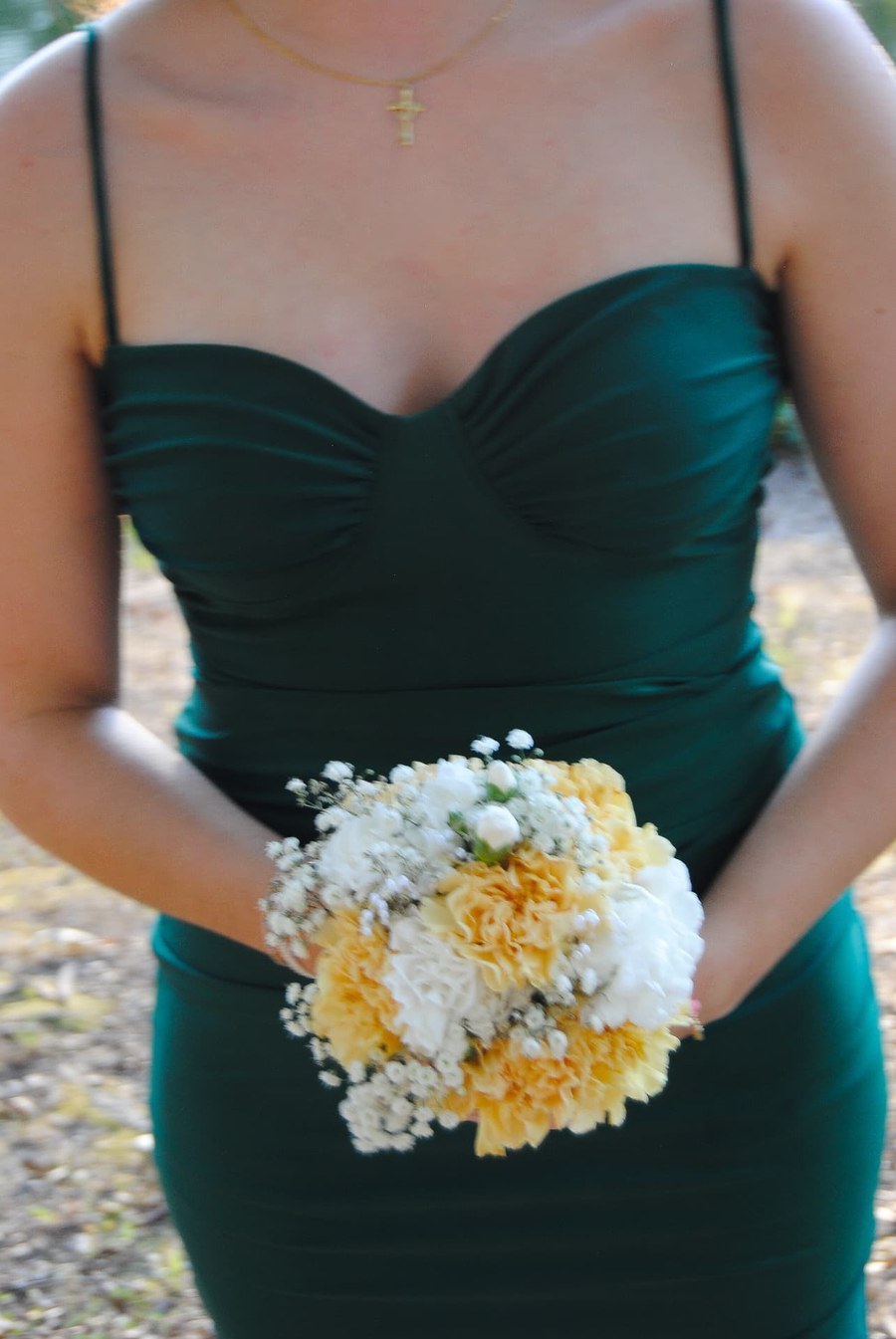 Bridesmaid in a green dress holding a bouquet of yellow and white flowers